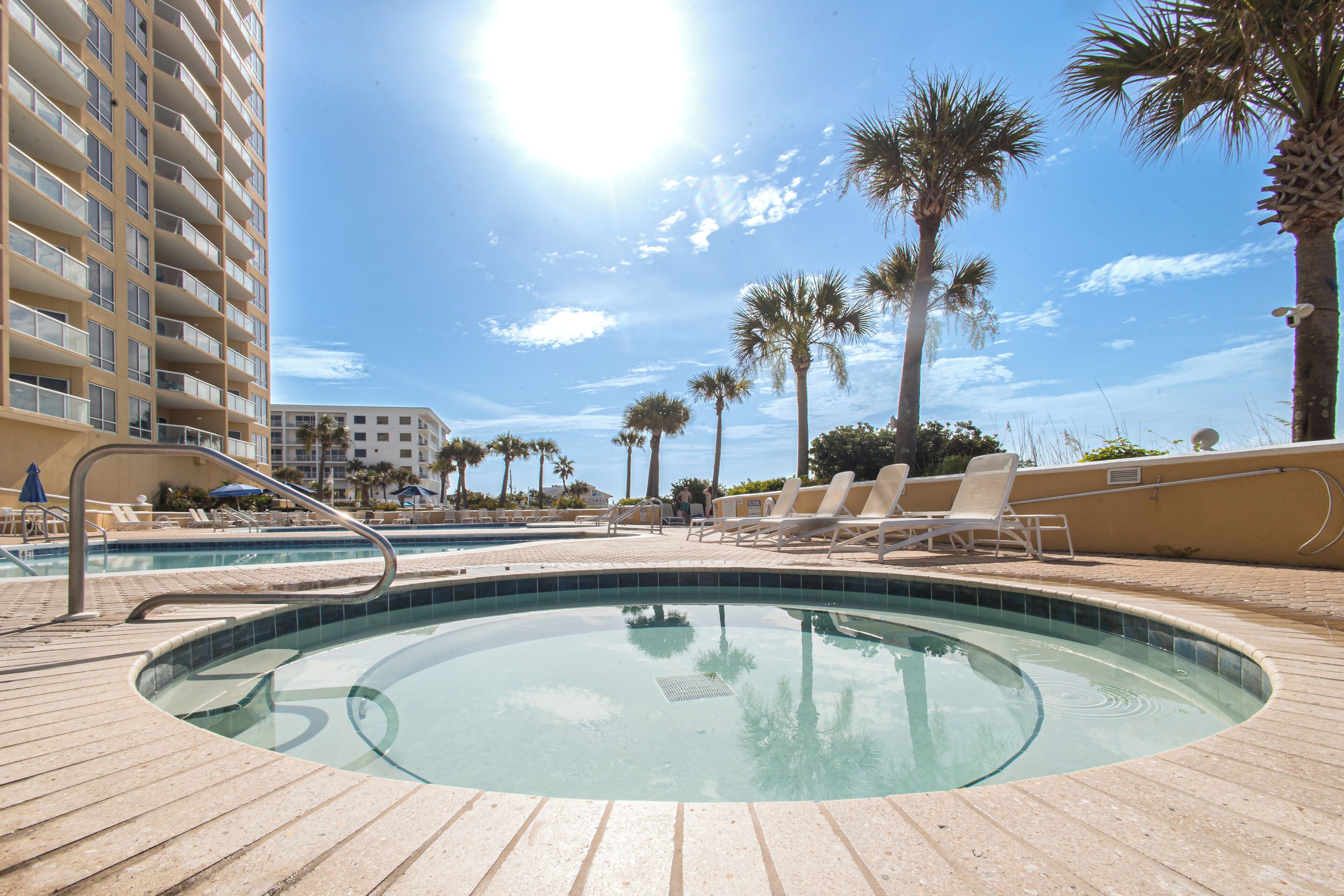 A swimming pool area with lounge chairs and palm trees.