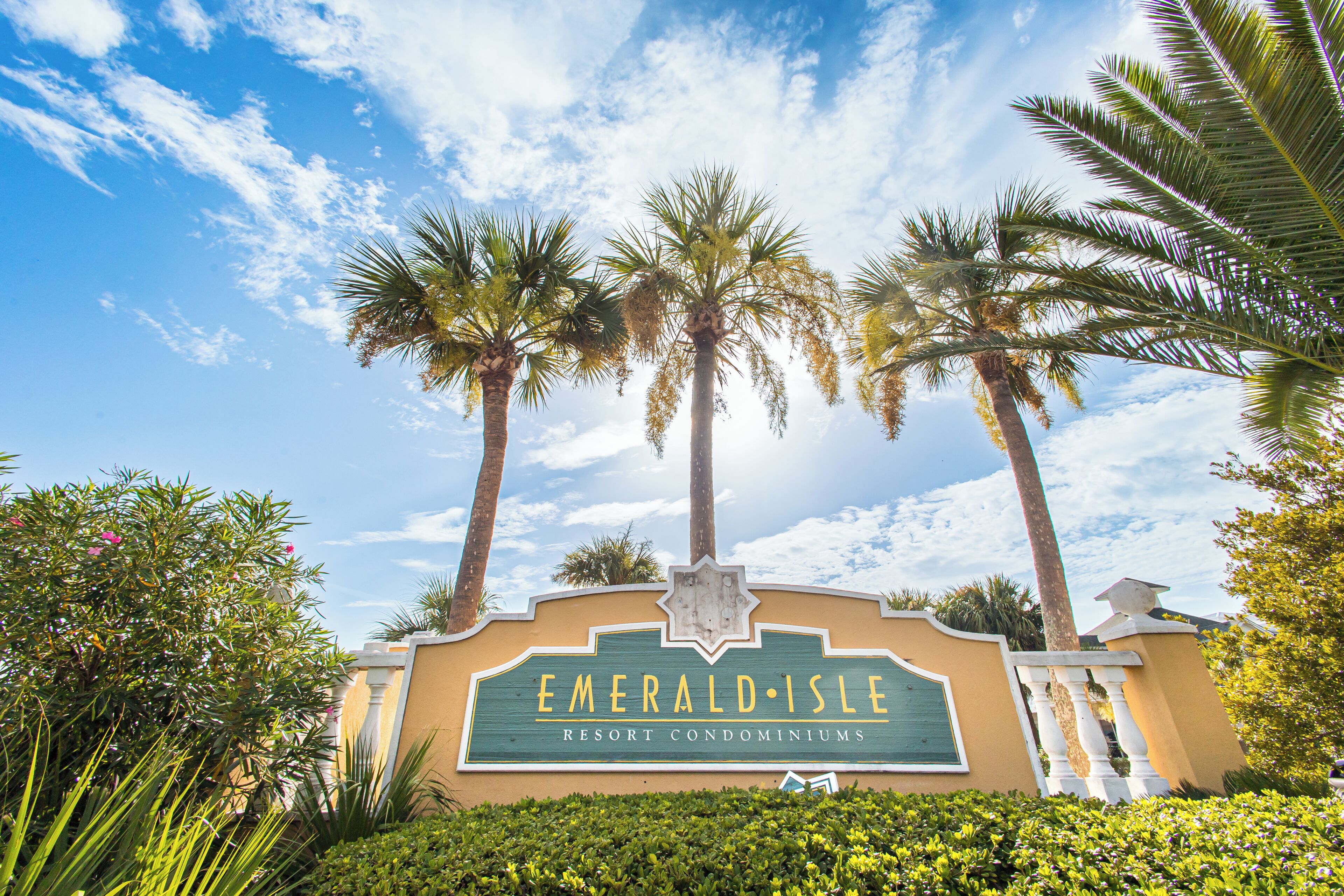 Une enseigne pour le complexe hôtelier Emerald Isle Resort, avec des palmiers et un ciel dégagé en arrière-plan.