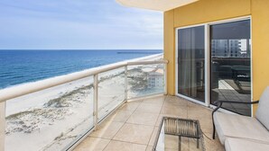A balcony with a view of the beach and ocean, a sliding glass door, and a small table with a chair. - 3B Gulf Front Paradise at Emerald Isle - 12th Floor (Pensacola Beach)