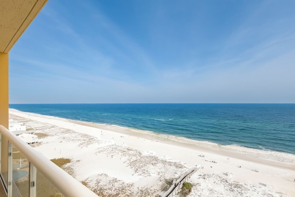 Blick auf einen Strand vom Balkon bei blauem Himmel.