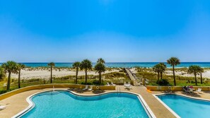 Ein Poolbereich mit zwei Pools, einer Holzterrasse und Blick auf den Strand.