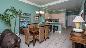 A dining area with wicker chairs, a wooden table, and a chandelier.