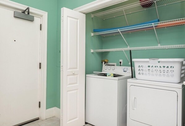 A laundry area with a washing machine, dryer, and shelves for hanging clothes.