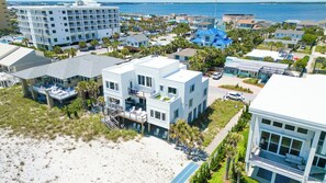 Un hotel costero con varias edificaciones, incluyendo un gran hotel de estilo turístico con zona de piscina y una construcción más pequeña con balcón.