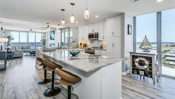 Una cocina moderna con una isla grande, taburetes de bar y vistas a la playa.