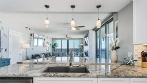 Una cocina moderna con una isla grande, electrodomésticos de acero inoxidable e iluminación colgante.