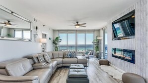 Un salón amplio con un sofá modular en forma de L, una chimenea y un televisor montado en la pared.