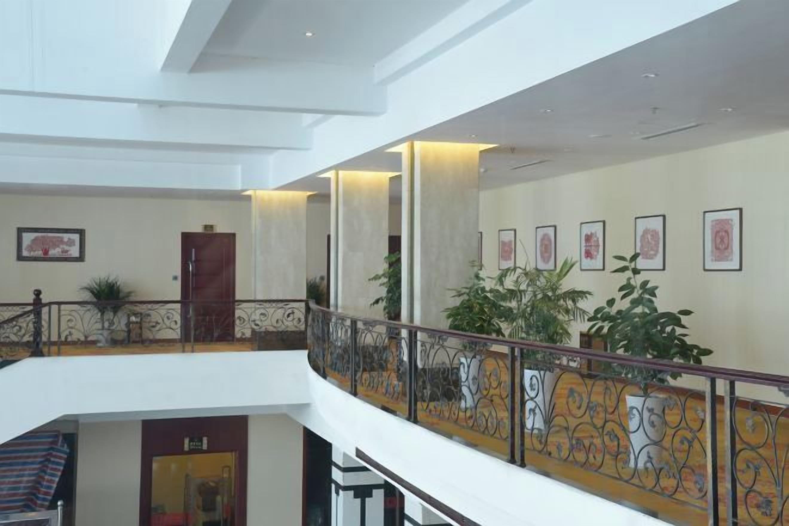 A multi-level interior with a staircase, railings, and framed artwork on the walls.