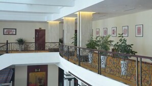Un interior con varios niveles, un balcón, barandillas y cuadros enmarcados en las paredes.