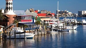 A marina with boats docked, a lighthouse, and buildings including a restaurant.