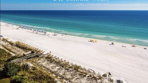 A beach with a clear view of the ocean, a sandy shore, and a few umbrellas and beach chairs.