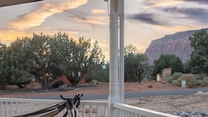 A hammock on a porch with a view of a desert landscape and mountains.