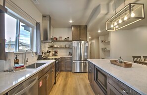Una cocina moderna con electrodomésticos de acero inoxidable, armarios de madera y un amplio ventanal que proporciona luz natural.