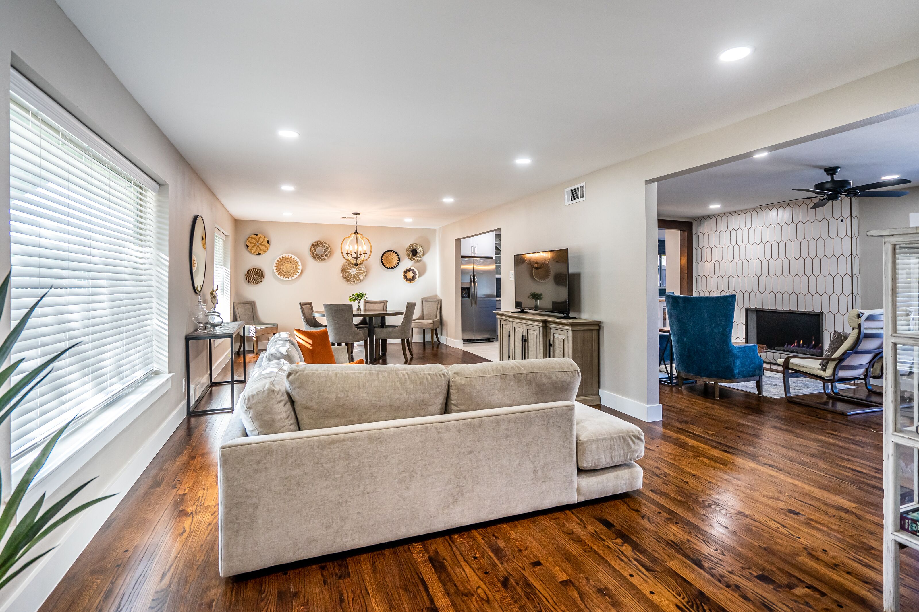 A modern living room with a sofa, dining area, kitchen, and a fireplace.