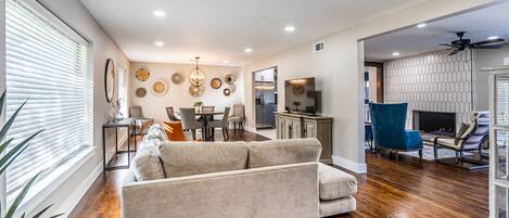 A modern living room with a sofa, dining area, kitchen, and a fireplace.