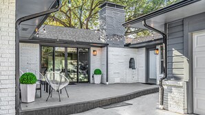 Een modern huis met een overdekte patio, een bakstenen schoorsteen en een garage.