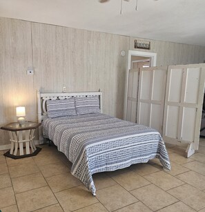 Ein Schlafzimmer mit Bett, Nachttisch mit Lampe, Kleiderschrank und Wandthermostat.