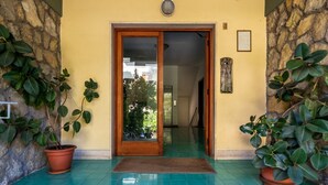 A building entrance with a wooden door, potted plants, and a tiled floor. - Azzurro Park Suite Sorrento (Sorrento)