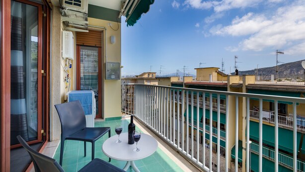 A balcony with two chairs, a small table, and a bottle of wine. - Azzurro Park Suite Sorrento (Sorrento)