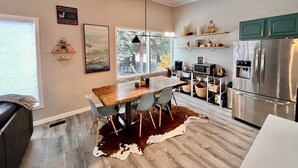 A modern kitchen with a wooden dining table, grey chairs, a cowhide rug, and a stainless steel refrigerator. - Mid-Century Modern Montana Dream Home (Butte)