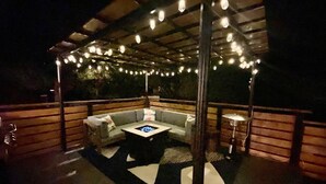 An outdoor patio with a sofa, a coffee table, and string lights. - Mid-Century Modern Montana Dream Home (Butte)