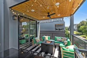 A modern outdoor patio with a ceiling fan, string lights, and a fire pit. - The Grove by AvantStay – Stylish Group Stay with Private Bathrooms (Nashville)