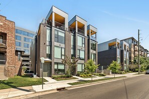 A modern apartment building with multiple balconies, large windows, and a well-maintained lawn. - The Grove by AvantStay – Stylish Group Stay with Private Bathrooms (Nashville)