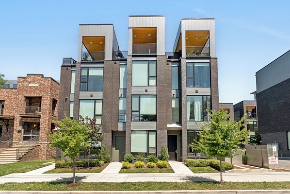 A modern multi-story building with a brick facade, large windows, and a central entrance. - The Grove by AvantStay – Stylish Group Stay with Private Bathrooms (Nashville)
