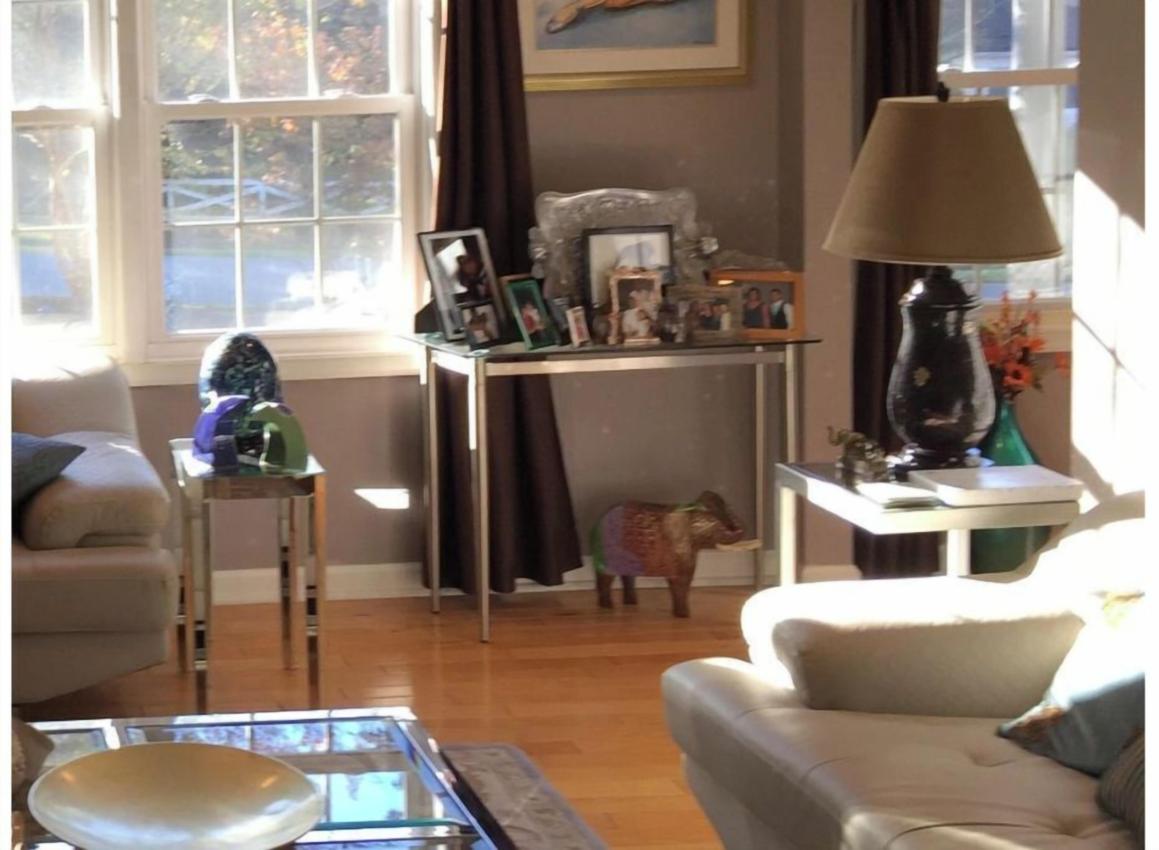 Uma sala de estar com sofá, mesa de centro, luminária e uma pequena mesa com diversos objetos.