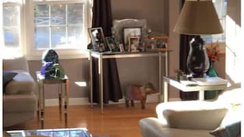 Uma sala de estar com sofá, mesa de centro, luminária e uma pequena mesa com diversos objetos.