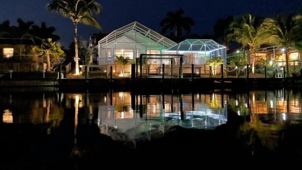 A modern hotel with a glass structure, a pool, and palm trees.
