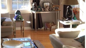 Un salon comprenant un canapé, une table basse, une lampe et une petite table sur laquelle sont posés divers objets.