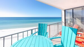 Ein Balkon mit türkisfarbenen Stühlen mit Blick auf einen Strand.