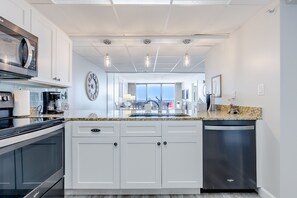 A modern kitchen with white cabinetry, a stainless steel microwave, and a dishwasher.