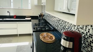 A modern kitchen with a gas stove, a microwave, and a coffee maker. - Sea View House, Luxury and Comfort (Porto Seguro)