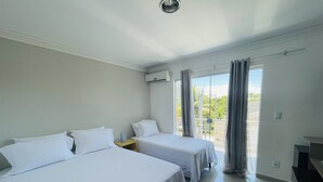 A hotel room with two beds, a balcony with curtains, and a view of greenery outside. - Sea View House, Luxury and Comfort (Porto Seguro)