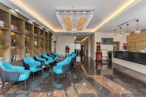 A lobby with a reception desk, seating area with chairs, and a bookshelf.