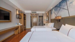 Habitación de hotel con dos camas, televisión, escritorio y un cuadro abstracto grande en la pared.