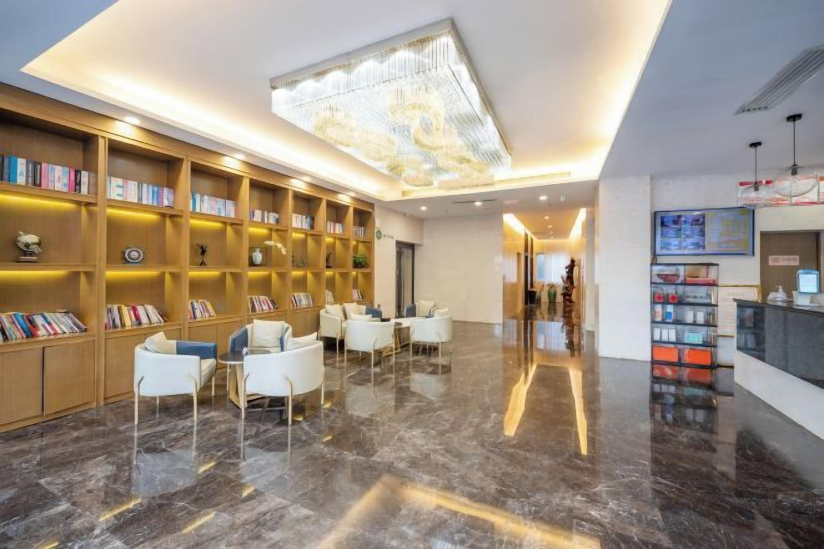 A lobby with a marble floor, a reception desk, and a bookshelf filled with books.