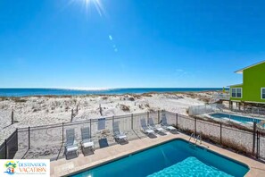 A pool area with lounge chairs and a view of the beach.