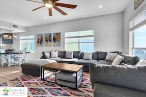 A spacious living room with a sectional sofa, a coffee table, and a colorful rug.