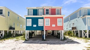 A multi-story beachfront property with a sandy ground floor and elevated wooden structures. - Luxury Beach House w/ Pool & Stunning Ocean Views (Gulf Shores)