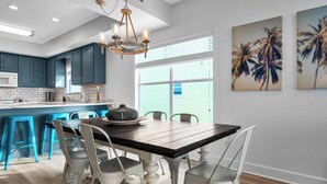 Une cuisine moderne avec des meubles de couleur turquoise, une table à manger en bois et une grande fenêtre.