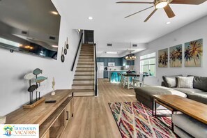 A modern living space with a staircase, a kitchen, and a dining area.
