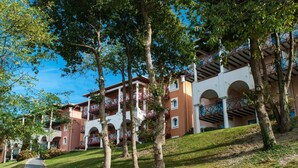 Un hotel con varios pisos, balcones exteriores y un camino de acceso a la entrada.