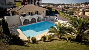 A residential property with a swimming pool, a covered patio, and a view of a residential area.