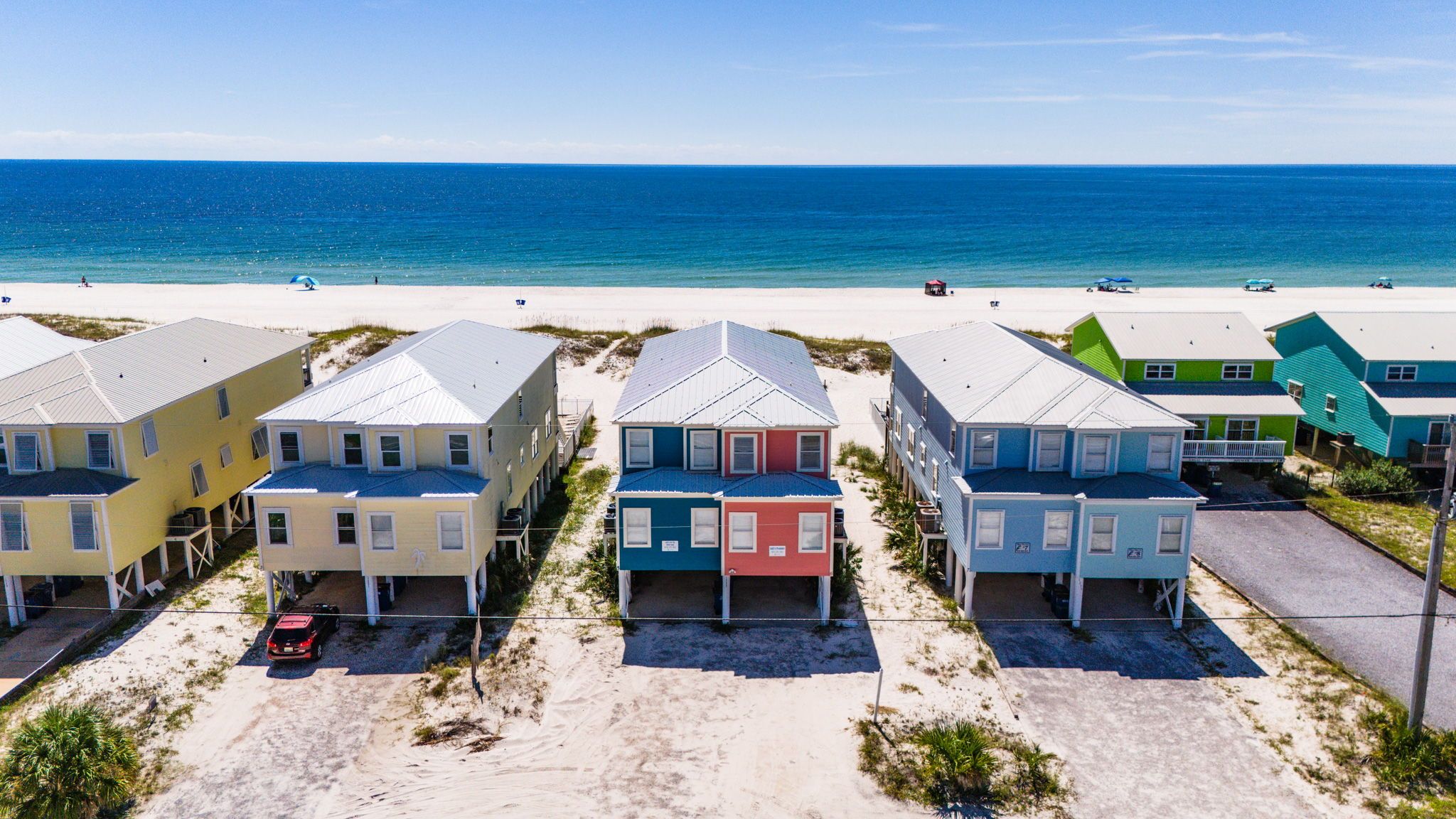 A beachfront property with multiple colorful houses, a sandy beach, and the ocean in the background.