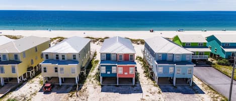 A beachfront property with multiple colorful houses, a sandy beach, and the ocean in the background.