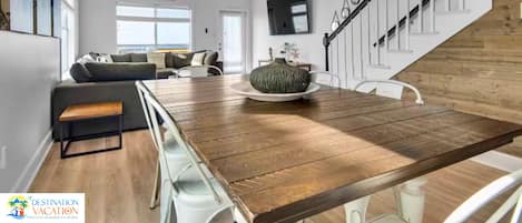 Ein geräumiges Wohnzimmer mit einem Holzesstisch, einer Sofagarnitur und einer Treppe.