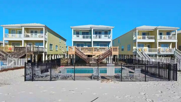 Ein direkt am Strand gelegenes Anwesen mit mehrstöckigen Gebäuden, einem Swimmingpool und einer Holzterrasse.